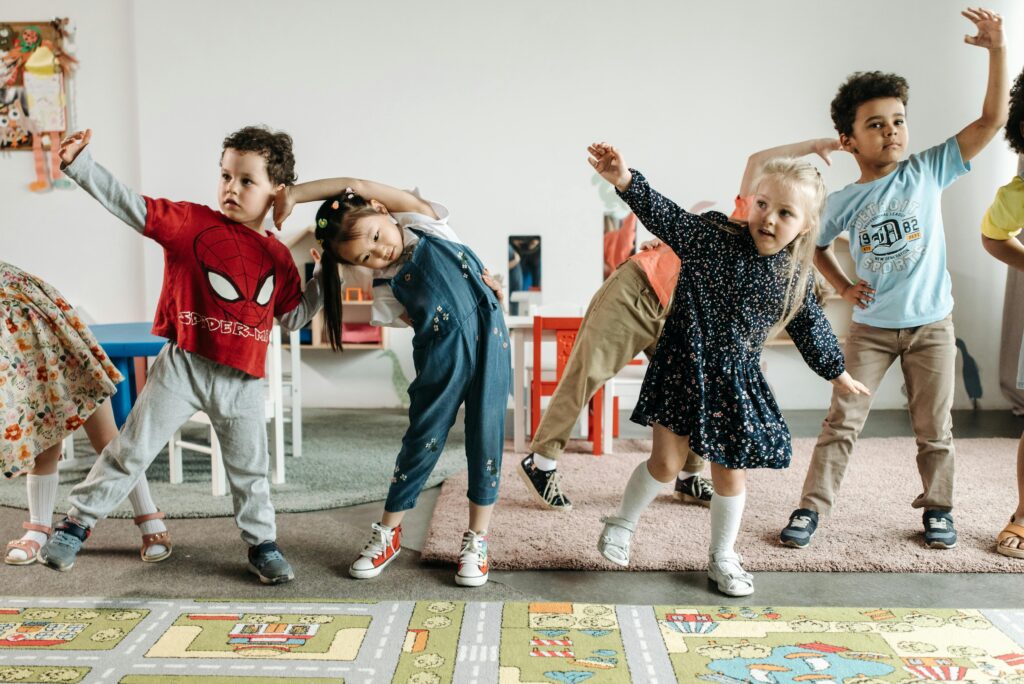 Children doing music and movements. Stretching their arms into the left and to the right.